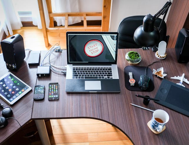 A contemporary office desk setup with laptops, gadgets, and accessories, creating a tech-savvy workplace.