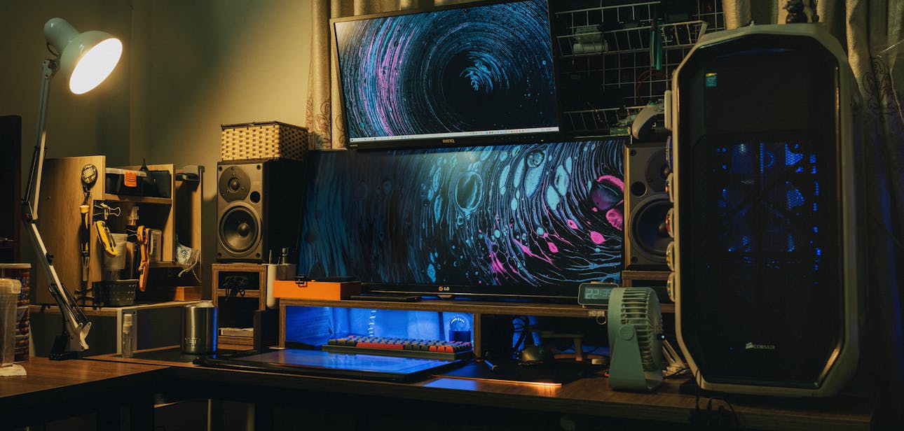 A cozy indoor modern computer setup with dual monitors and creative lighting.