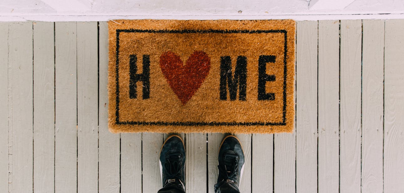 A creative doormat with heart motif symbolizing home at a front porch entrance.