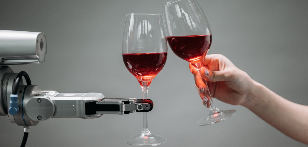A robot and a human hand clinking glasses of red wine, symbolizing technology and celebration.