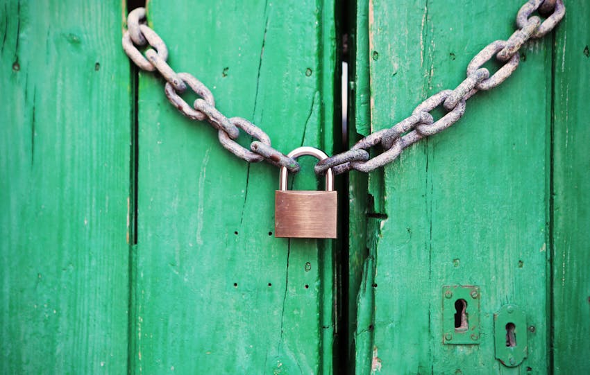 A rustic green wooden door secured with a heavy chain and padlock, symbolizing security.