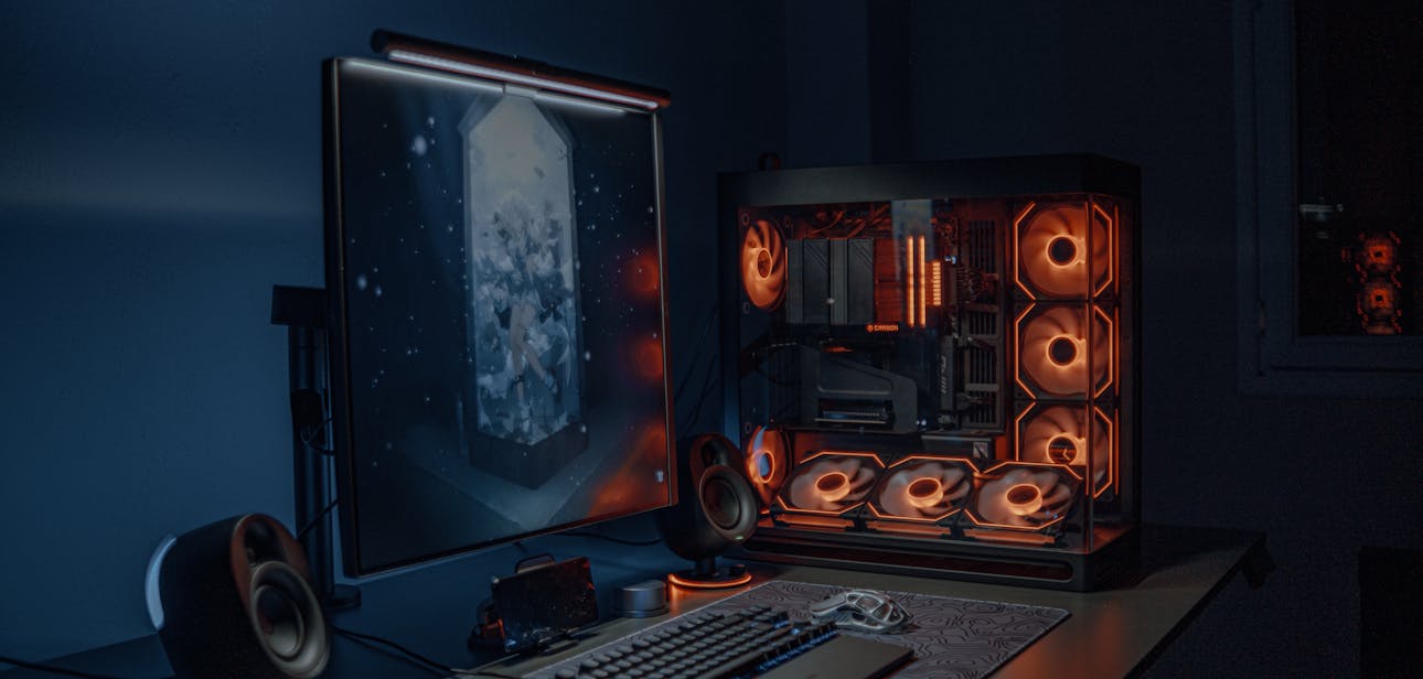 A sleek gaming PC setup with LED lights, monitor, and keyboard in a dimly lit room.