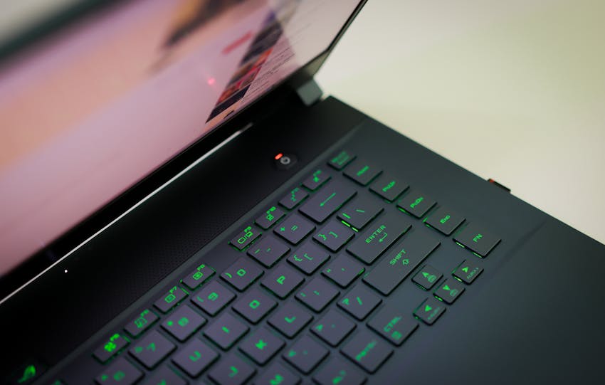 A sleek laptop with a glowing green keyboard illuminated, showcasing modern technology.