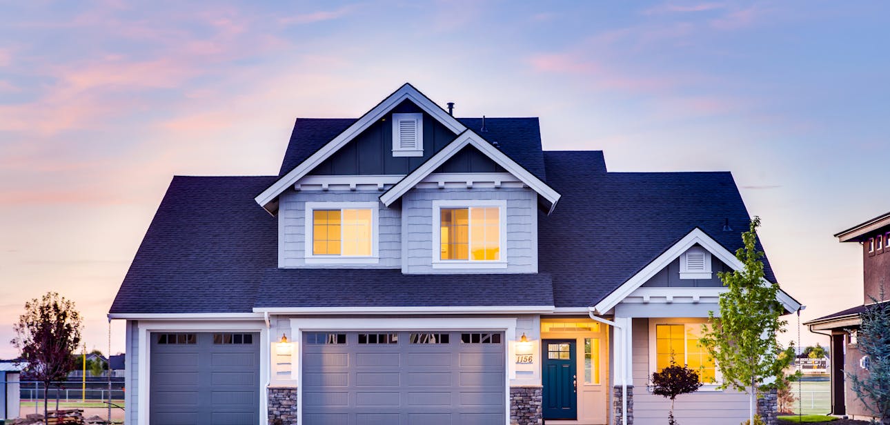 Beautiful two-story house with illuminated windows and garage at dusk.