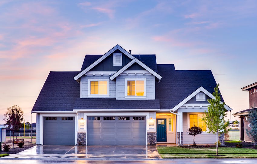 Beautiful two-story house with illuminated windows and garage at dusk.