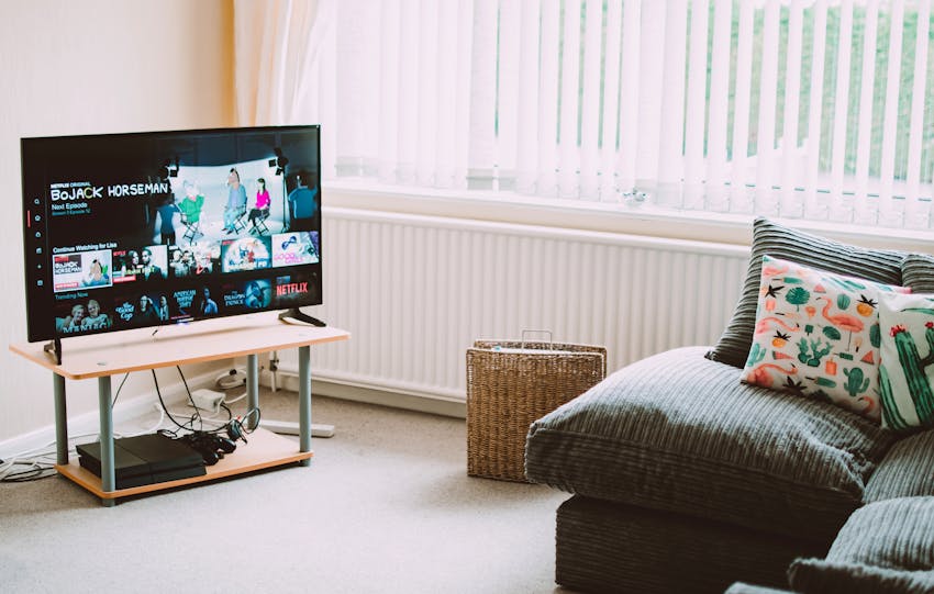 Chic and comfortable living room featuring a modern sofa, decorative pillows, and a TV streaming popular shows.