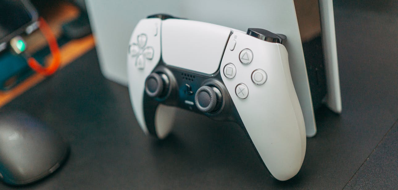 Close-up of a PlayStation 5 controller resting on its console, showcasing modern gaming technology.