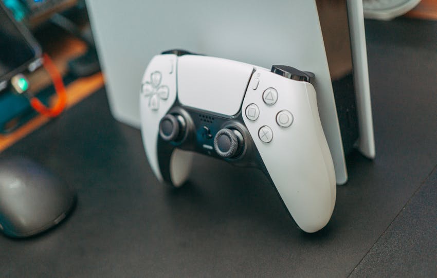 Close-up of a PlayStation 5 controller resting on its console, showcasing modern gaming technology.