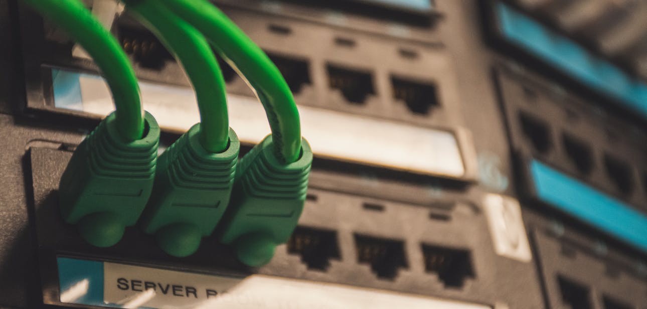 Close-up of green network cables plugged into server ports, showcasing technology setup.