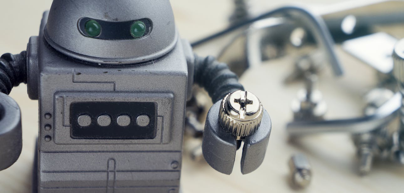 Detailed view of a toy robot holding a metallic screw, surrounded by tools.