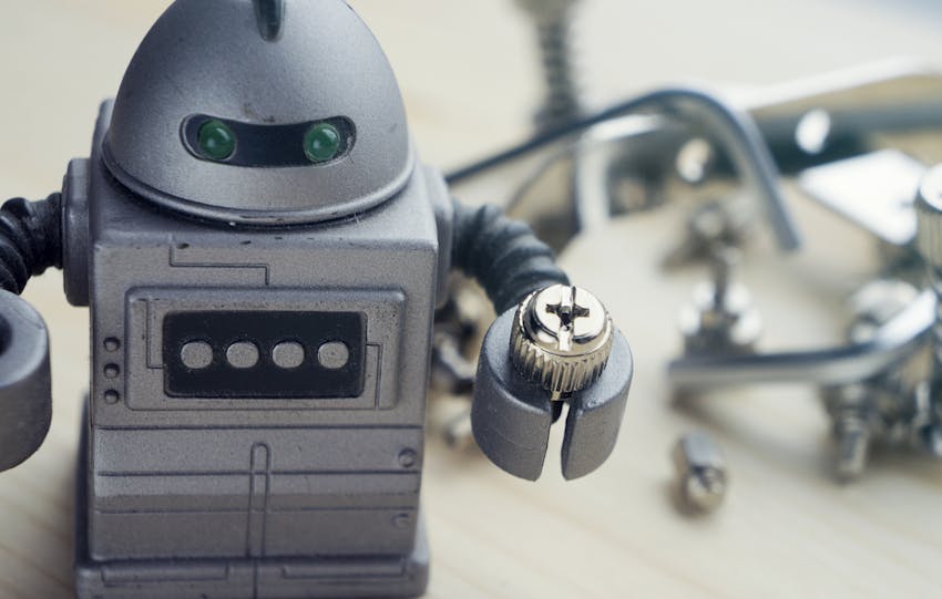 Detailed view of a toy robot holding a metallic screw, surrounded by tools.