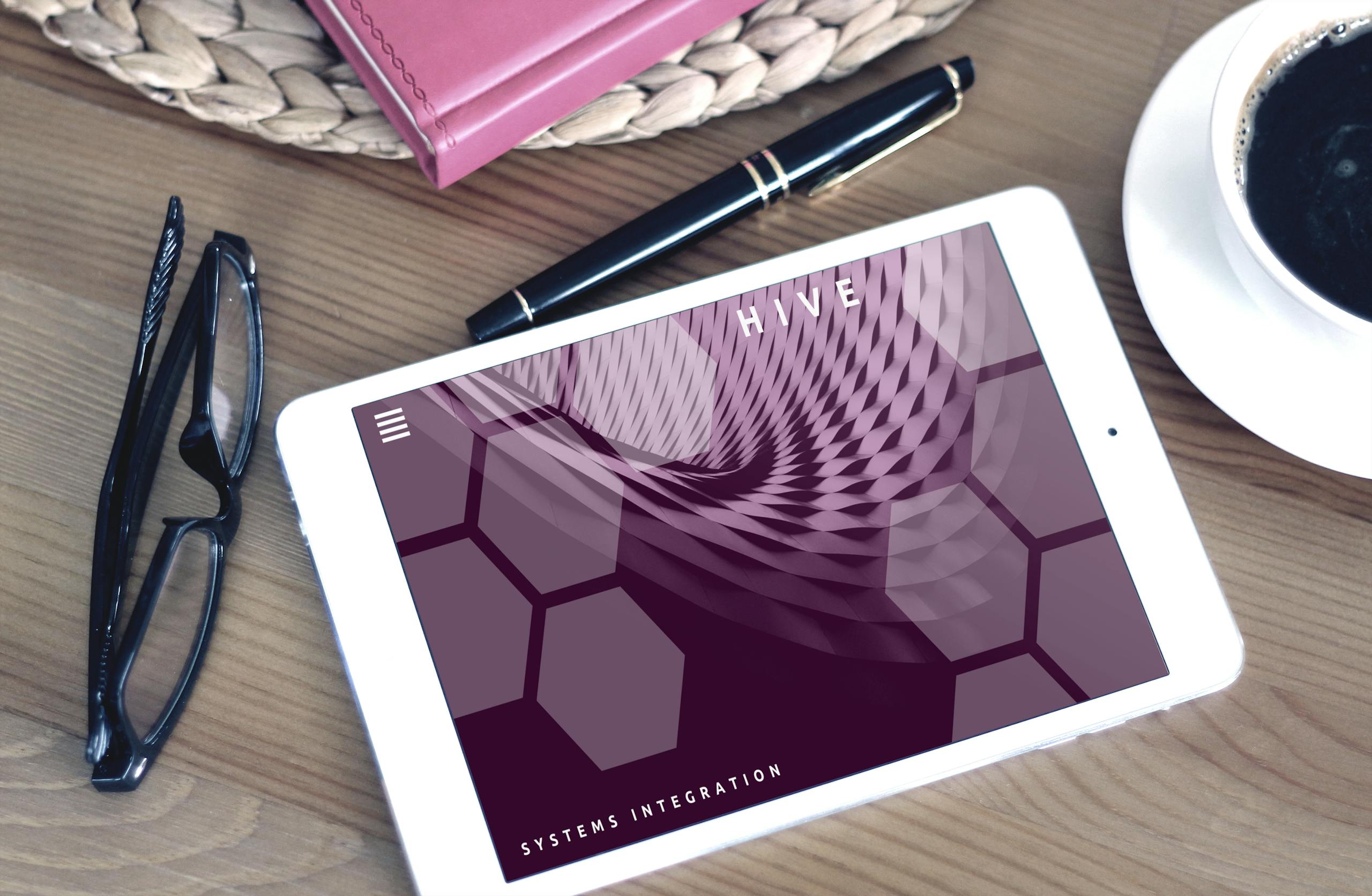 Flat lay of a modern workspace featuring a tablet displaying a screen, glasses, coffee, and a pen on a wooden desk.