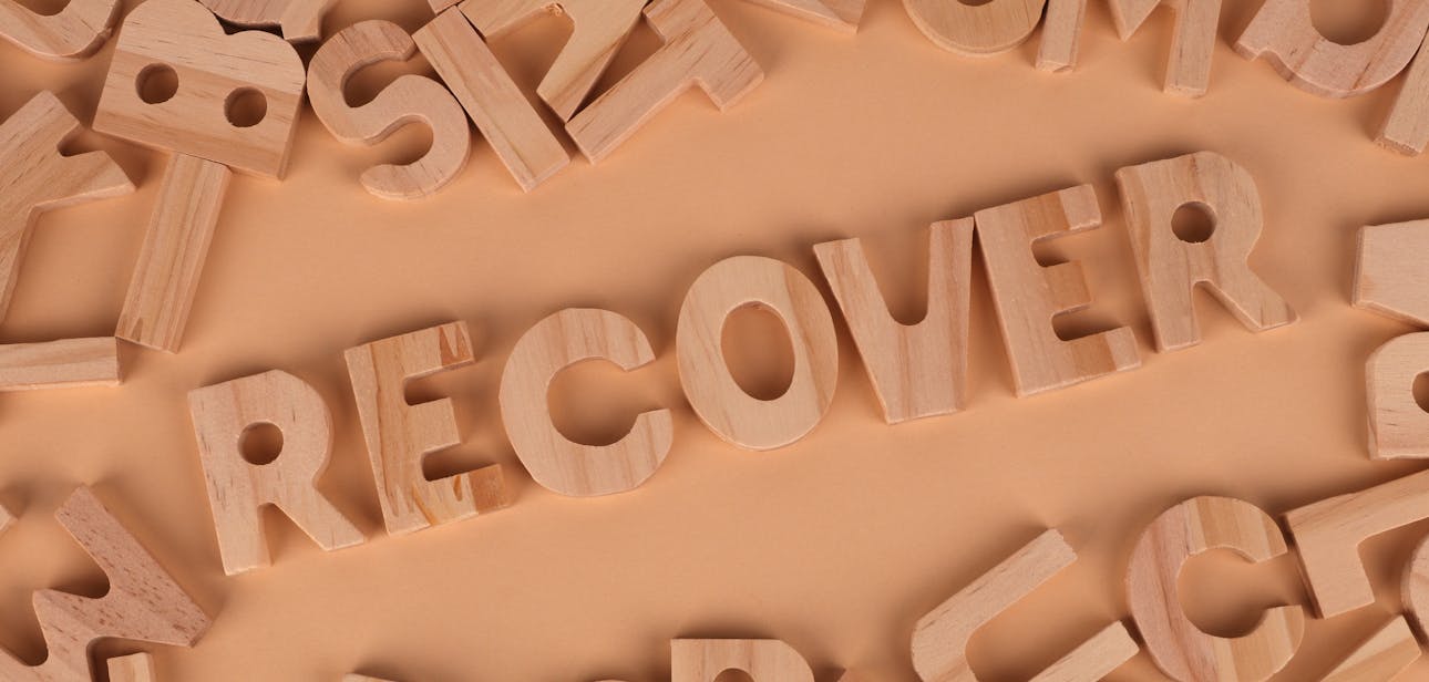 Flat lay of wooden alphabet letters with 'recover' highlighted.