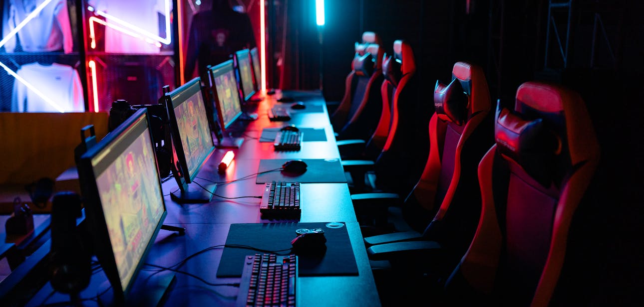 High-tech gaming setup with PCs, RGB lighting, and gaming chairs in a gaming house.