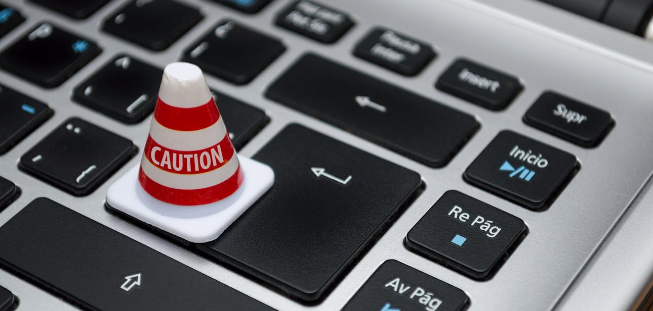 Miniature caution cone on a computer keyboard symbolizing data security and control.