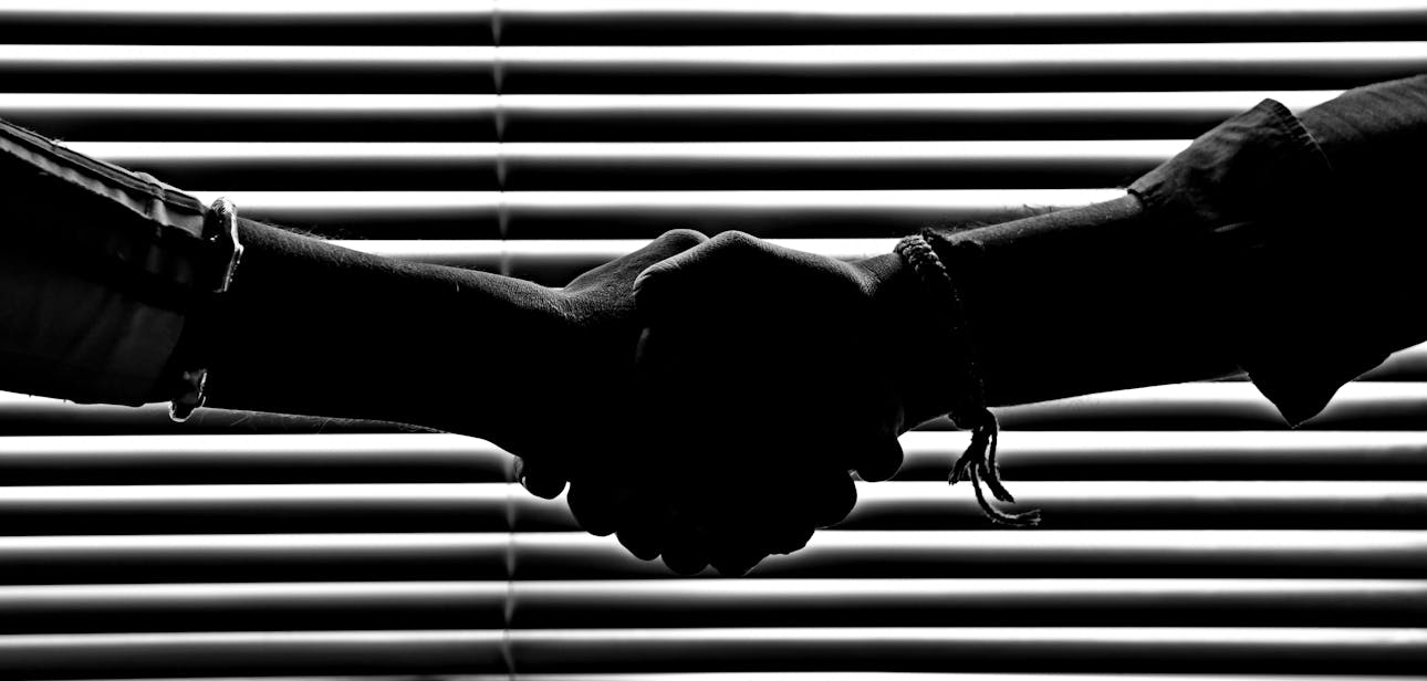 Silhouette of two people shaking hands symbolizing partnership and trust.