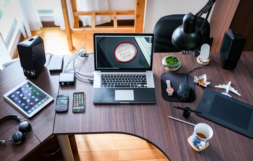 A contemporary office desk setup with laptops, gadgets, and accessories, creating a tech-savvy workplace.