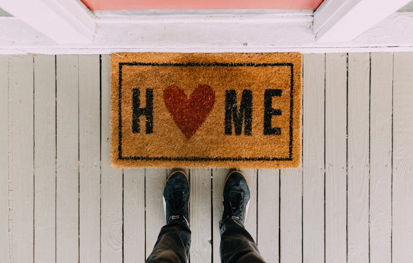 A creative doormat with heart motif symbolizing home at a front porch entrance.