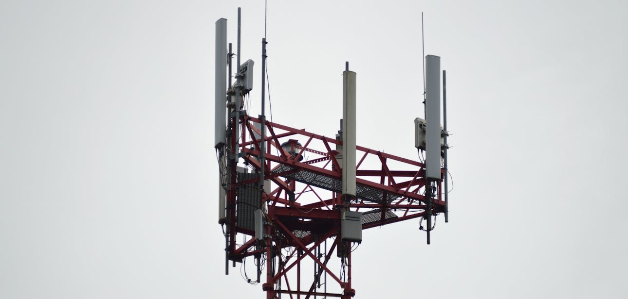 A red communication tower with antennas stands tall against a gray sky.