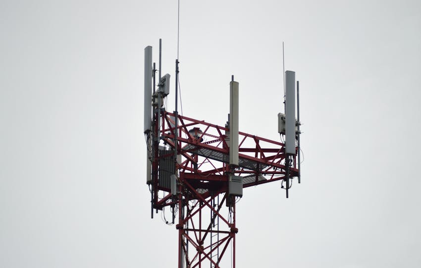A red communication tower with antennas stands tall against a gray sky.