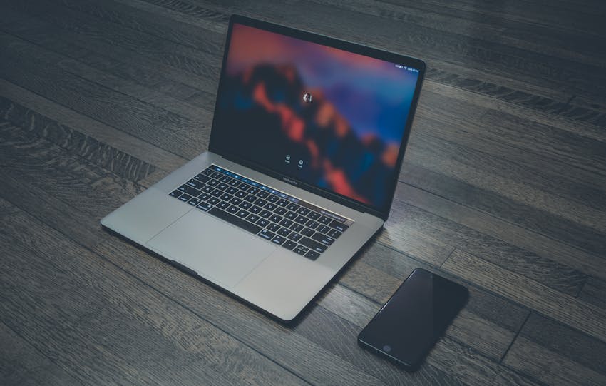 A sleek laptop and smartphone placed on wooden flooring, showcasing contemporary technology.