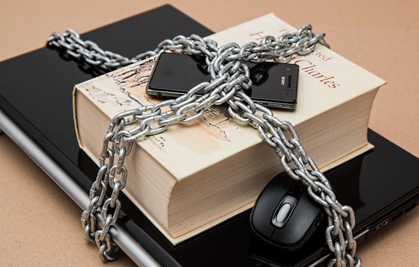 Chain-locked book, phone, and laptop symbolizing digital and intellectual security.