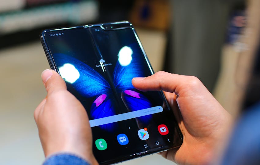Close-up of hands holding a foldable smartphone showing a butterfly on the screen.