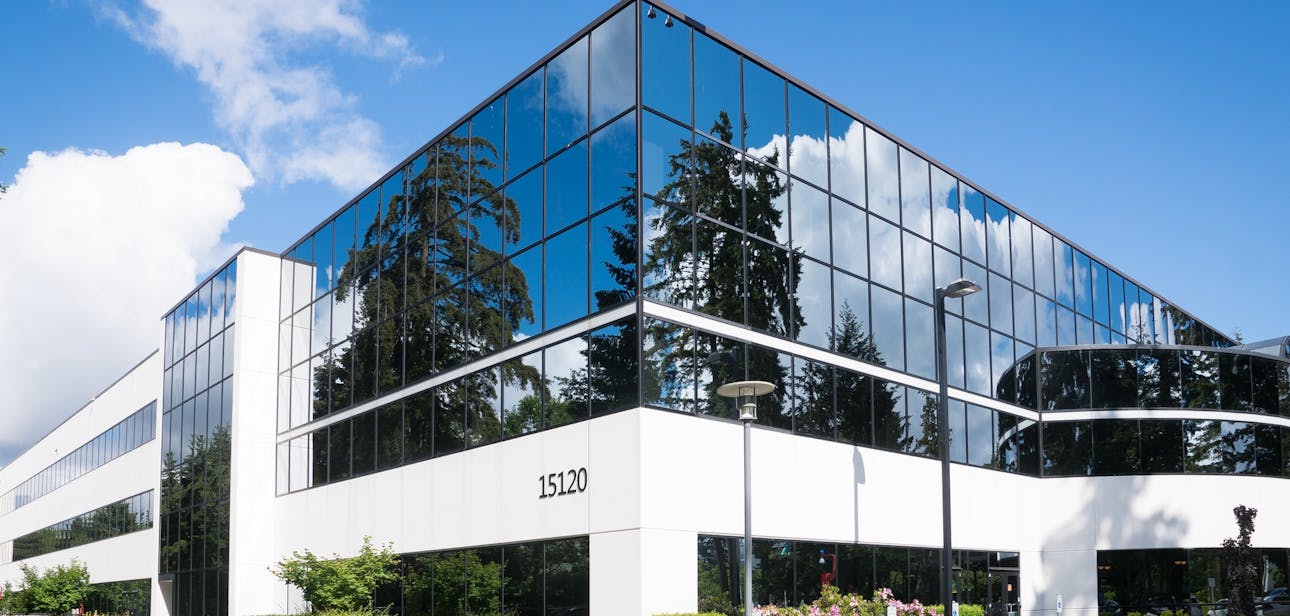 Contemporary office building in Redmond with reflective glass and lush greenery, captured on a sunny day.