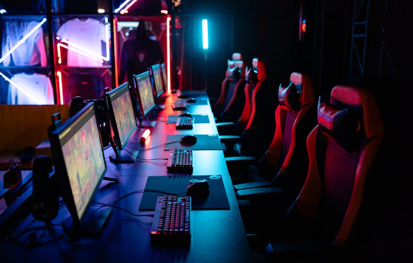 High-tech gaming setup with PCs, RGB lighting, and gaming chairs in a gaming house.